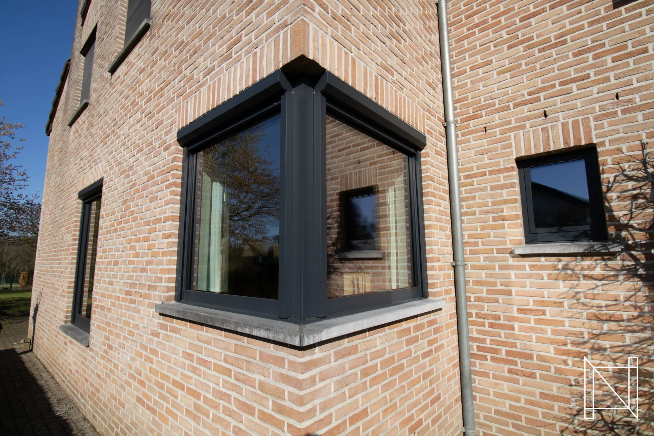 Detail van een aluminium hoekraam in een bakstenen gevel