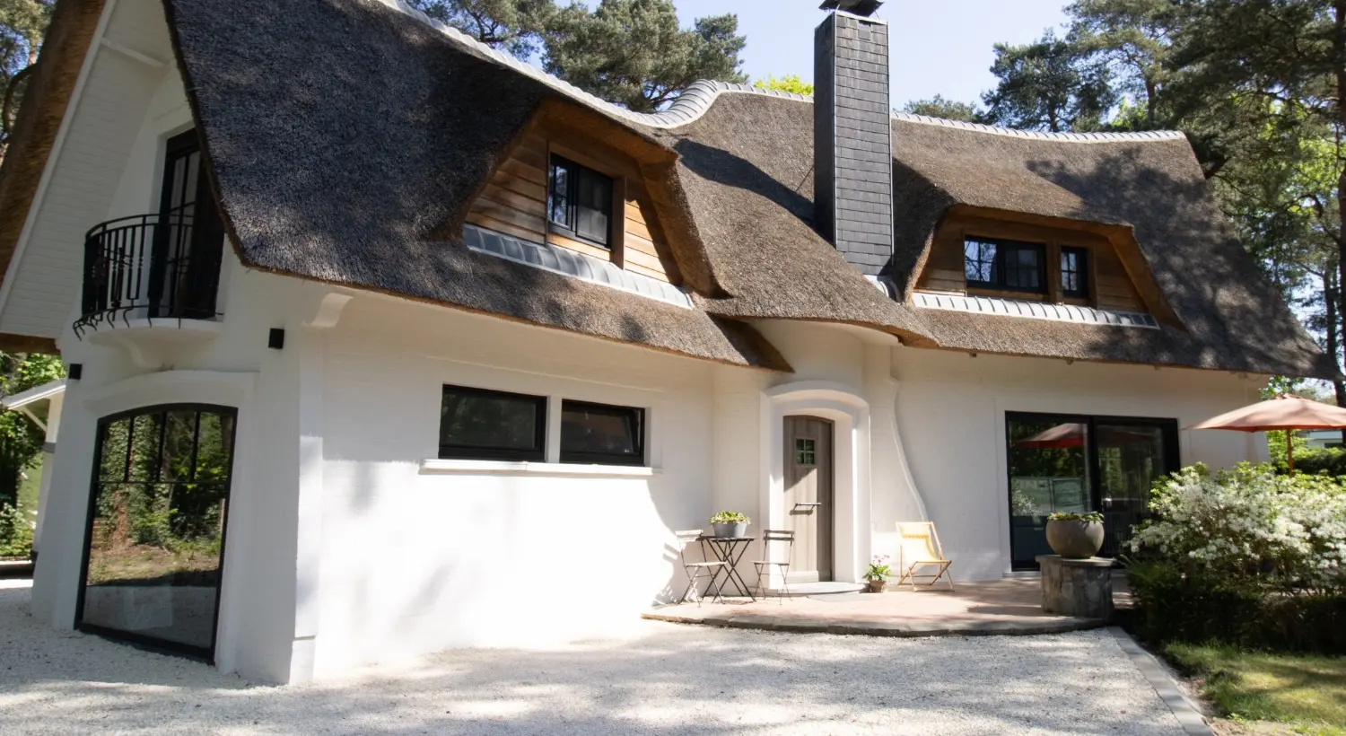 Woning met rieten dak en donkere PVC ramen
